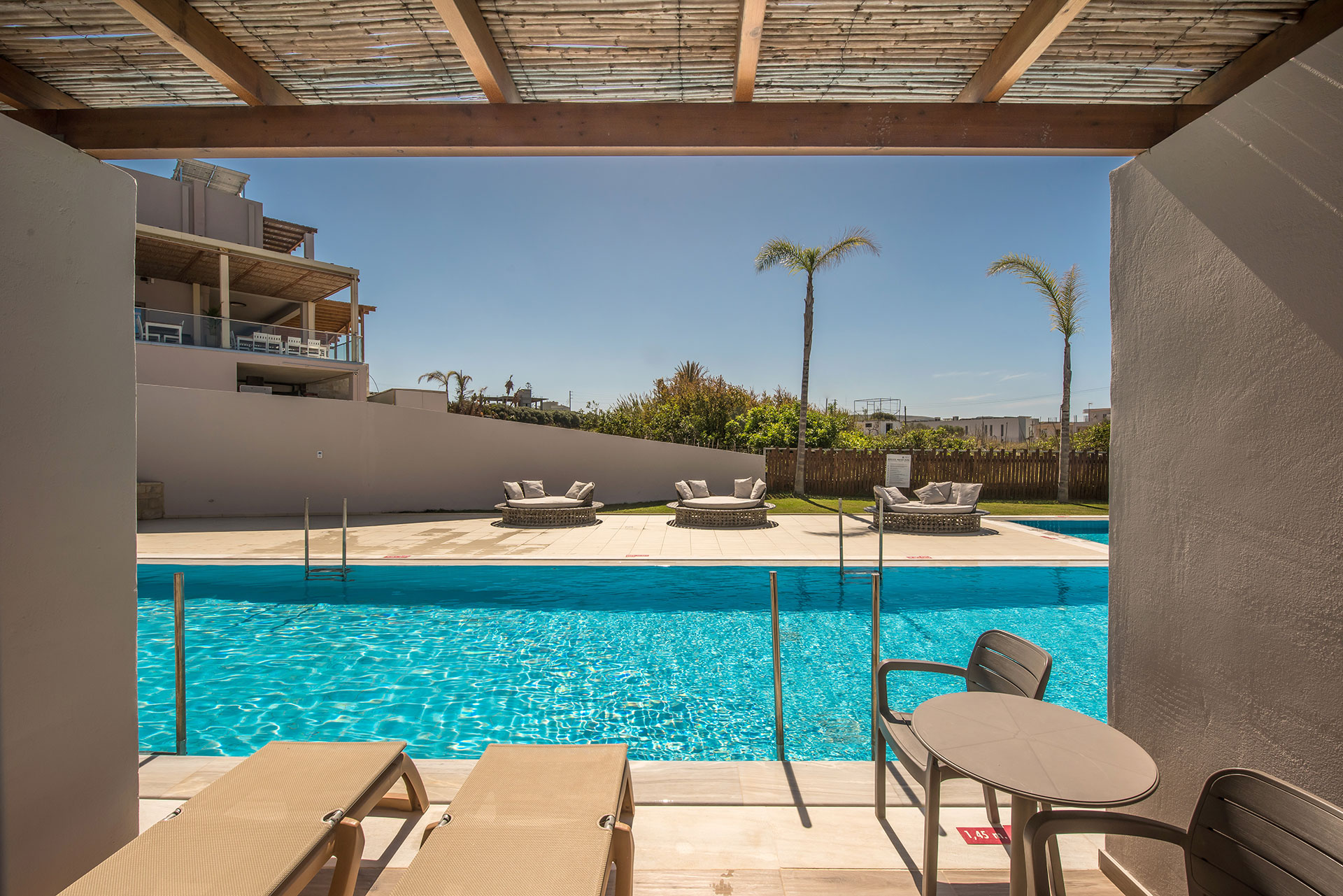 Swim Up maisonette outdoor lounge with sunbeds and table next to the shared pool at Gouves Water Park Holiday Resort