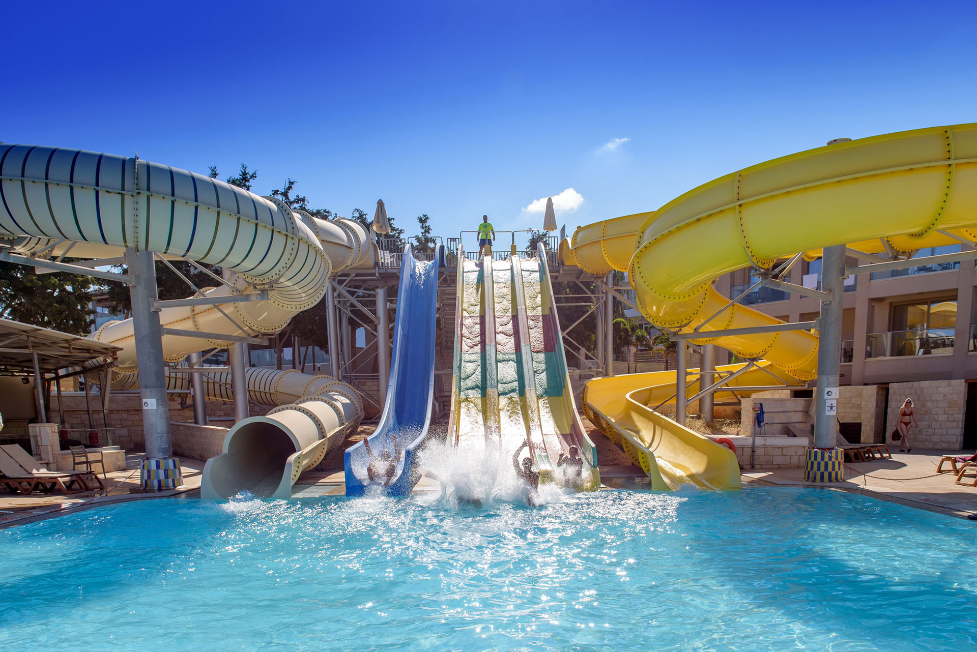 Guests splashing into the pool from high speed water slides at Gouves Water Park Holiday Resort in Crete