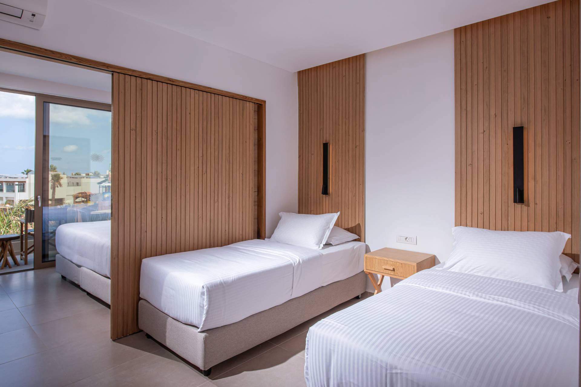 Premium family suite room with two single beds, wooden divider leading to the double bed area and balcony at Gouves Water Park Holiday Resort