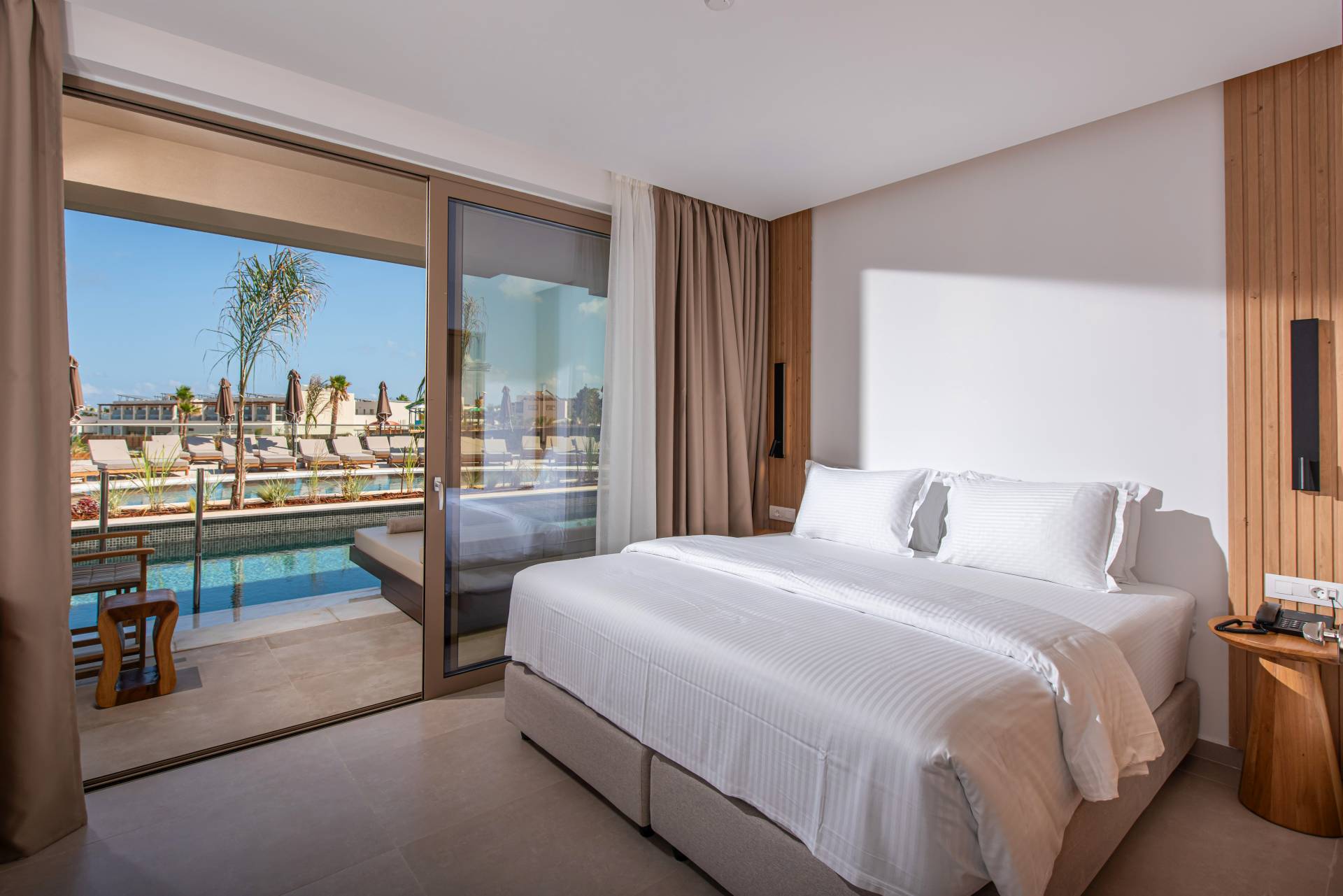 Premium family suite swim up bedroom with large balcony doors opening to the poolside terrace and cozy double bed at Gouves Water Park Holiday Resort